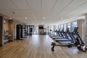 A gym with treadmills, exercise equipment, and large windows. - Hilton Arlington Rosslyn The Key (Arlington)