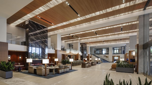 A spacious lobby with a high ceiling, modern lighting, and comfortable seating areas. - Hilton Arlington Rosslyn The Key (Arlington)