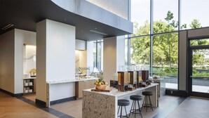 A modern kitchen with a marble island, bar stools, and a view of the outdoors. - Hilton Arlington Rosslyn The Key (Arlington)