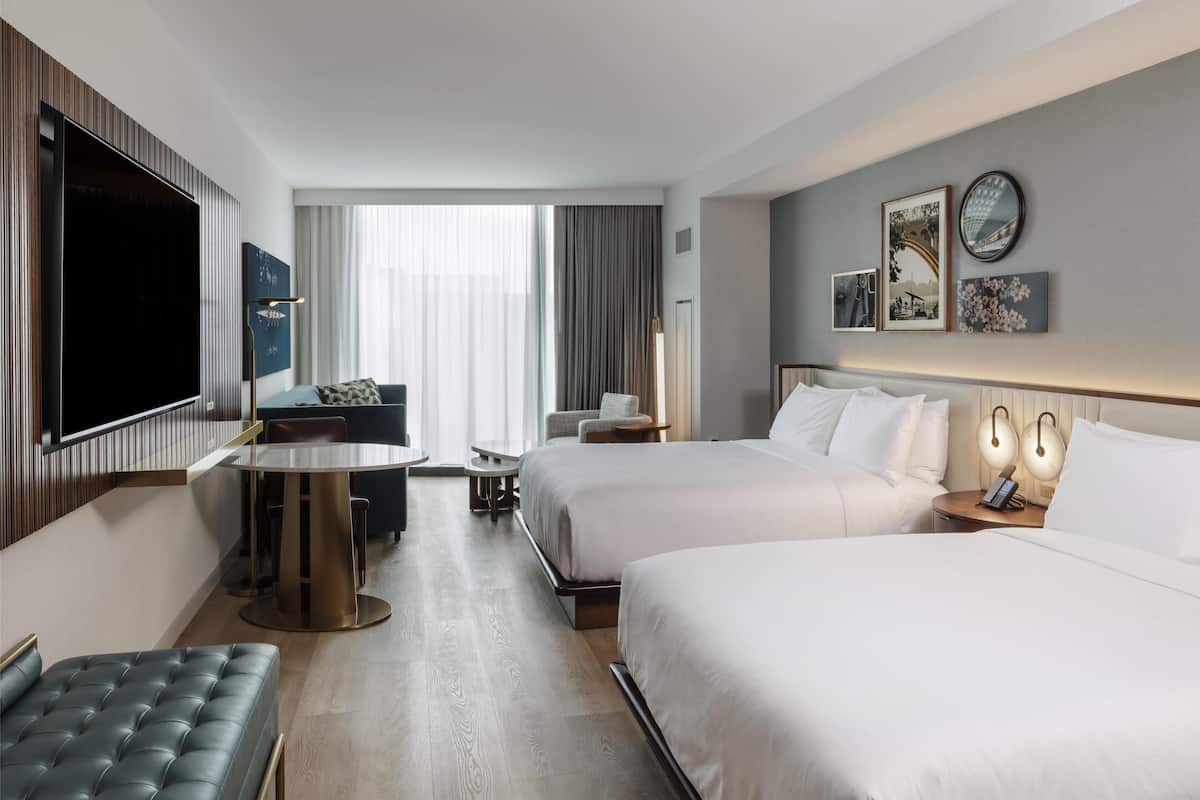 Une chambre d’hôtel avec deux lits, une télévision, une table à manger et un coin salon.