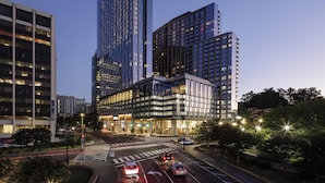 A modern high-rise building with multiple floors, large windows, and a well-lit entrance area. - Hilton Arlington Rosslyn The Key (Arlington)