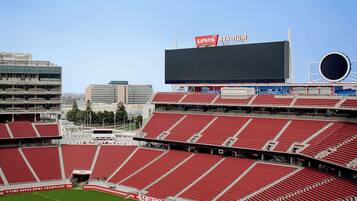 Un estadio con varios niveles de asientos rojos, un marcador digital grande y un letrero destacado que dice "Levi's Stadium".