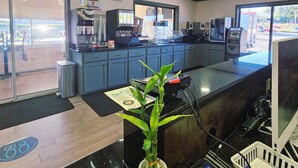 A modern interior with a reception desk, a coffee machine, and a large window offering a view of the outside.
