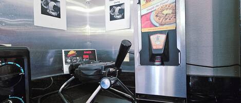 A kitchen with a coffee machine, a waffle maker, and a bread machine. There are signs instructing to rotate after closing.