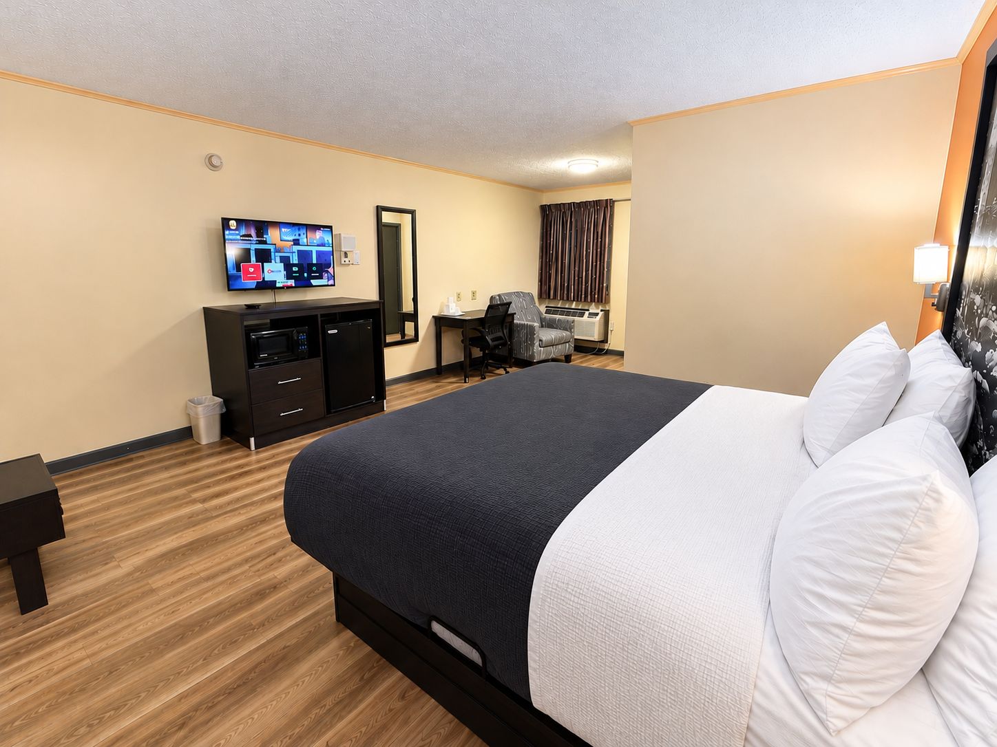 Una habitación de hotel con una cama grande, un escritorio, un televisor y un espejo.