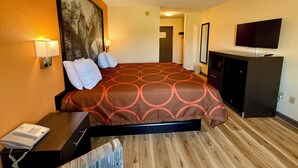 A hotel room with a large bed, a desk with a telephone, a television on a cabinet, and a painting on the wall.