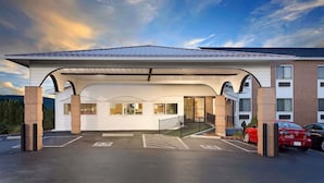 A hotel entrance with a covered parking area, brick pillars, and a clear sky.