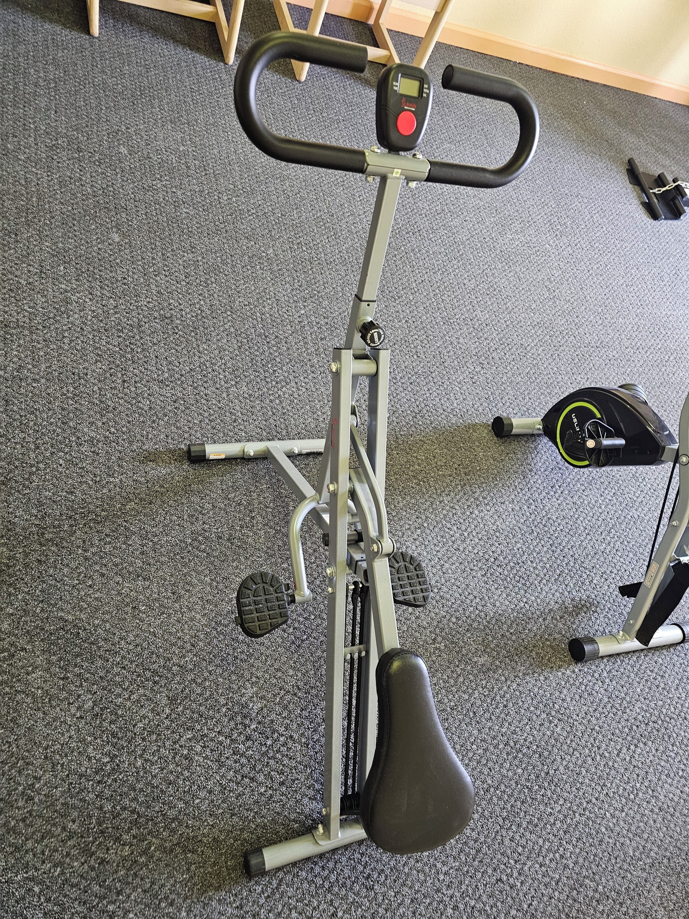 An exercise bike with a digital display, foot pedals, and a seat.