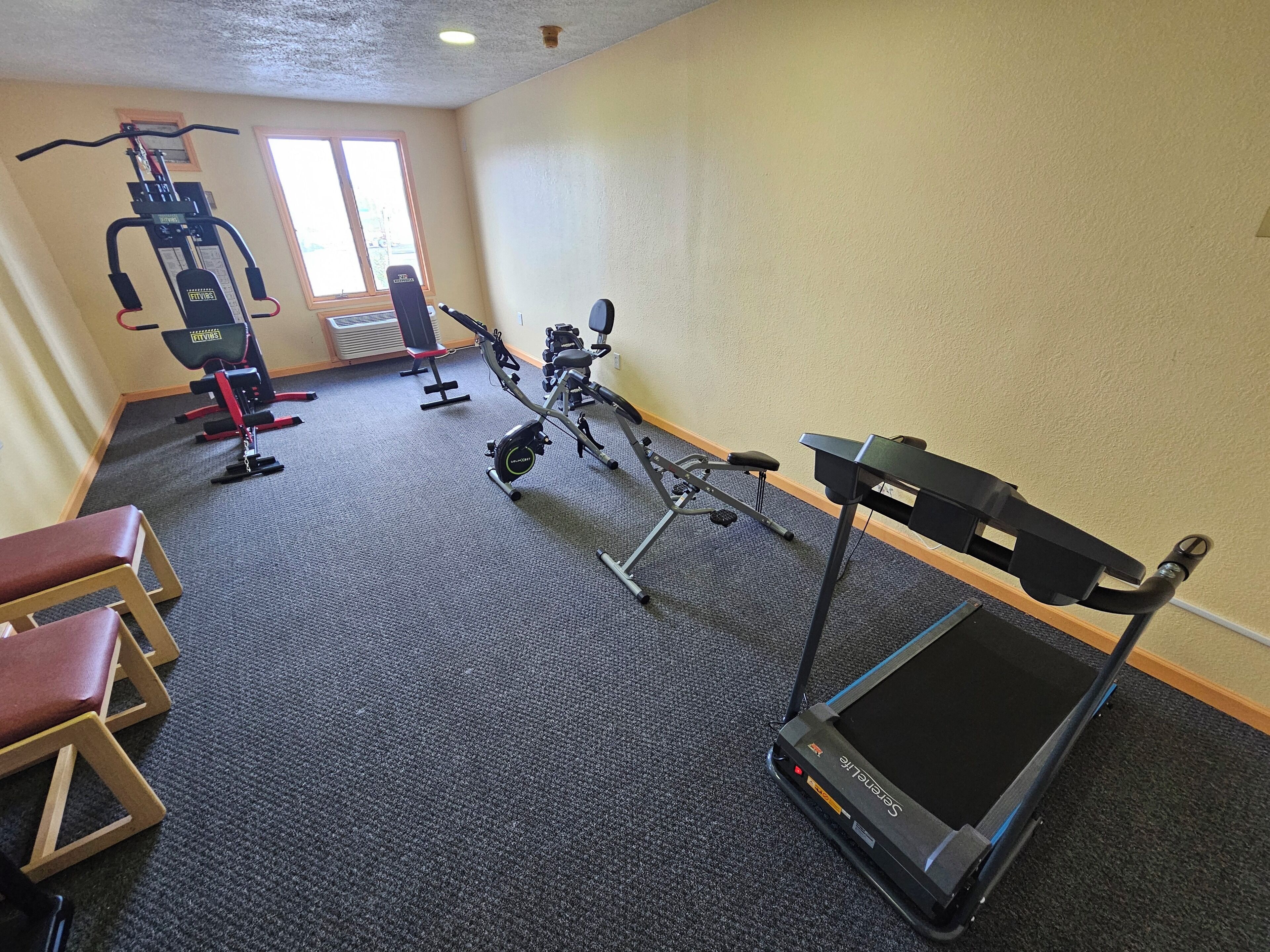A gym with cardio equipment, weight machines, and benches.