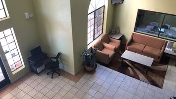 En stue med sofa, sofabord, et skrivebord med computer og en potteplante.