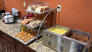 A buffet setup with various food items including pastries, muffins, and sandwiches.