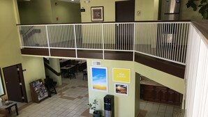 A spacious indoor area with a high ceiling, a staircase, and a balcony with a railing.