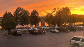 A parking lot with various vehicles, trees, and a bridge in the background. - Hotel Hanna (Harrisburg)