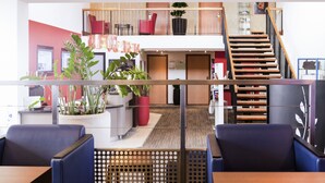 Un moderno vestíbulo de hotel con una recepción, un área de descanso y una escalera.