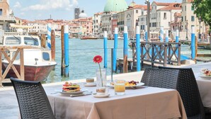 A table set for breakfast with a view of Venice's canals and historic buildings. - Santa Chiara Hotel (Venice)