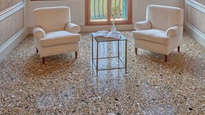 A room with two armchairs, a small table, and a large chandelier. There are large windows with a view of buildings and a balcony. - Santa Chiara Hotel (Venice)