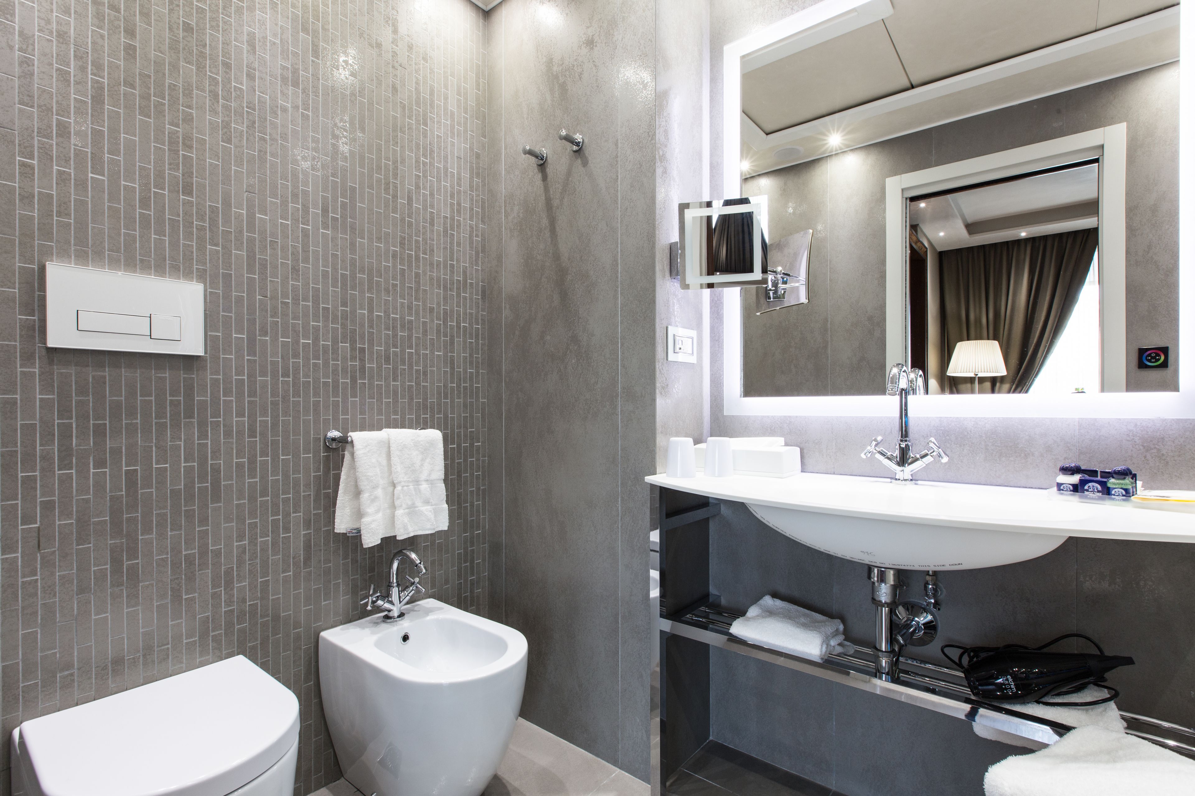 A modern bathroom with a bidet, a toilet, a sink, and a mirror.