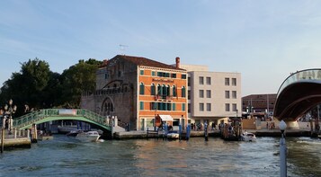 Un canale con imbarcazioni, un ponte verde e edifici, tra cui uno con un cartello che riporta 'Santa Maria delle Grazie'.