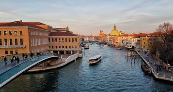 Un canale con barche, un ponte pedonale e palazzi lungo l'acqua.
