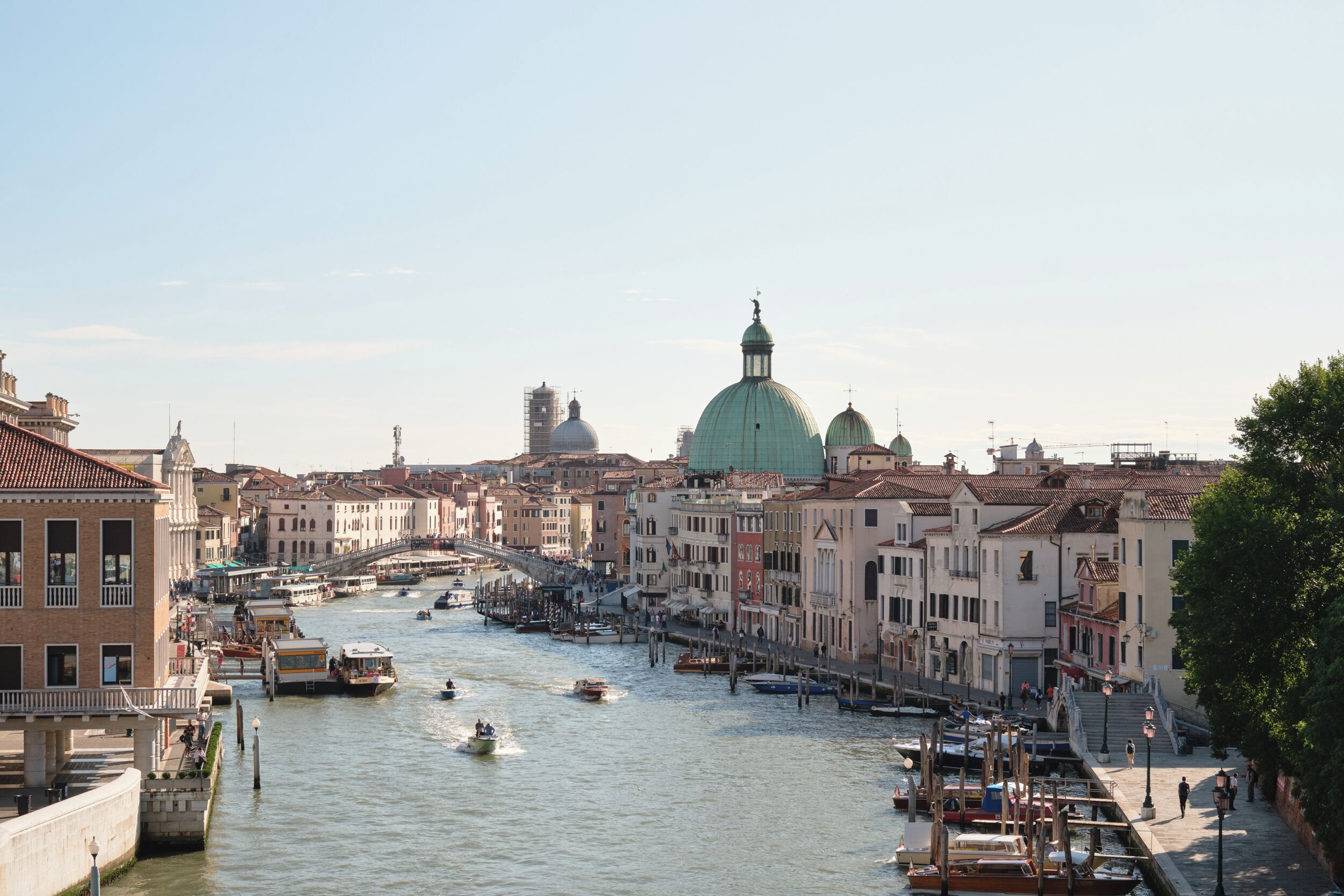 A canal with boats, historic buildings, and a prominent dome structure.