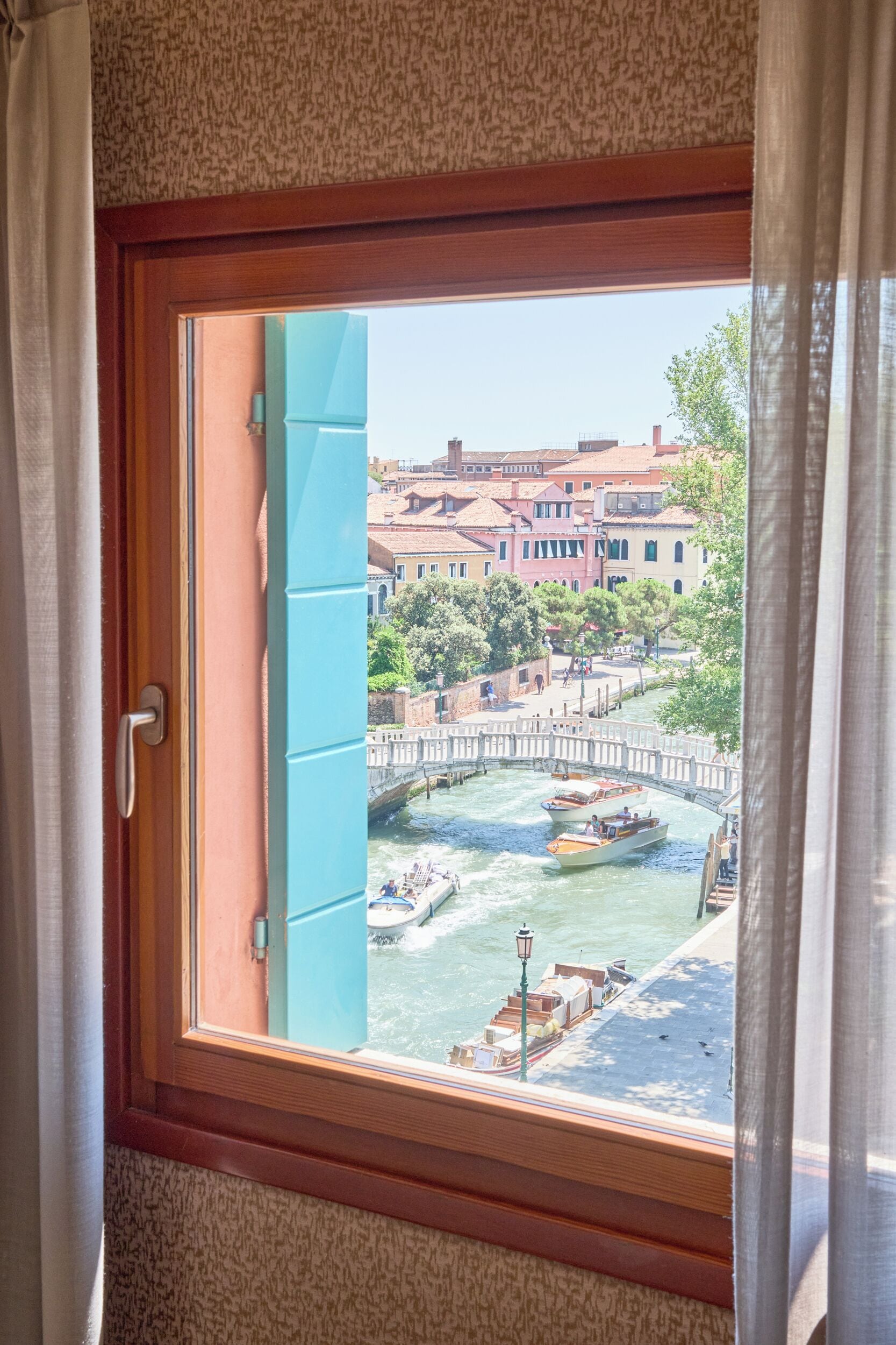 Ein Fenster mit Blick auf einen Kanal, Boote und Gebäude.