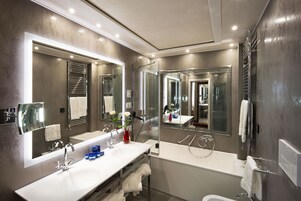 A modern bathroom with a large mirror, a white sink, and a bathtub.