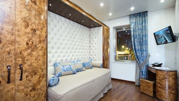 A bedroom with a large bed, a wardrobe, a television, and a window with curtains.