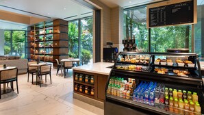 A modern cafe with a large window view, a counter with pastries, and a display of bottled drinks. - JW Marriott Atlanta Buckhead (Atlanta)
