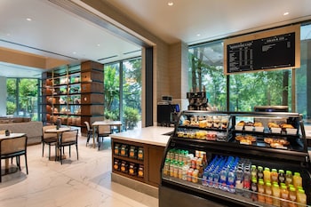 A corner seating area with a view of the city skyline, a round table with a plant, and a bookshelf. at JW Marriott Atlanta Buckhead