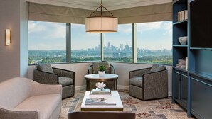A corner seating area with a view of the city skyline, a round table with a plant, and a bookshelf. - JW Marriott Atlanta Buckhead (Atlanta)