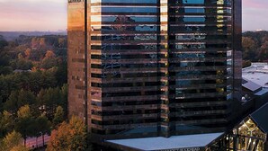 A JW Marriott Buckhead hotel with a modern glass facade, surrounded by autumn foliage. - JW Marriott Atlanta Buckhead (Atlanta)