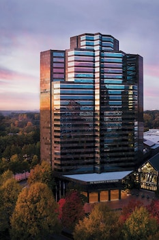 An indoor swimming pool with clear blue water, surrounded by white columns and chairs, and a glass ceiling above. at JW Marriott Atlanta Buckhead