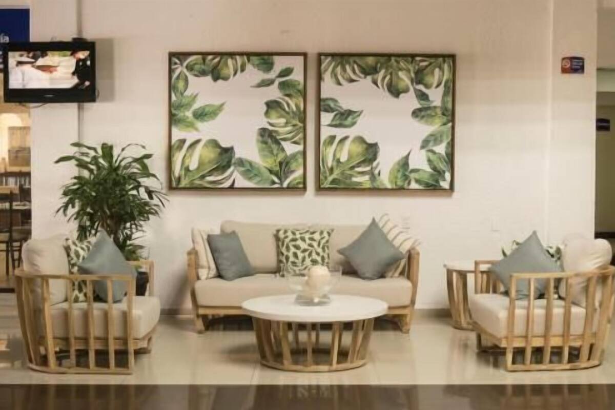 Ein Zimmer mit einer Couch, zwei Sesseln, einem Couchtisch und einem an der Wand befestigten Fernseher.