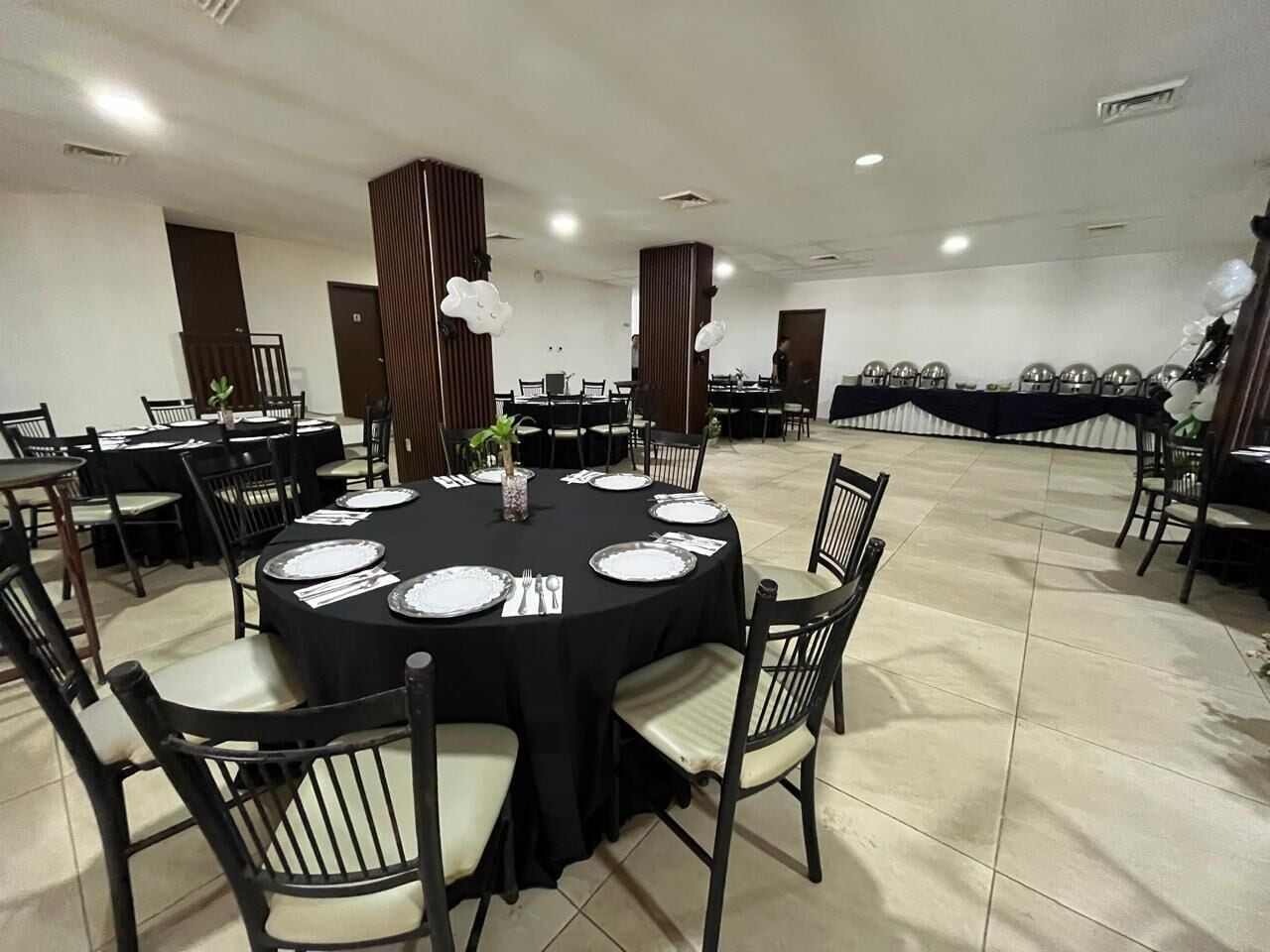 A conference room with round tables, black tablecloths, and chairs.