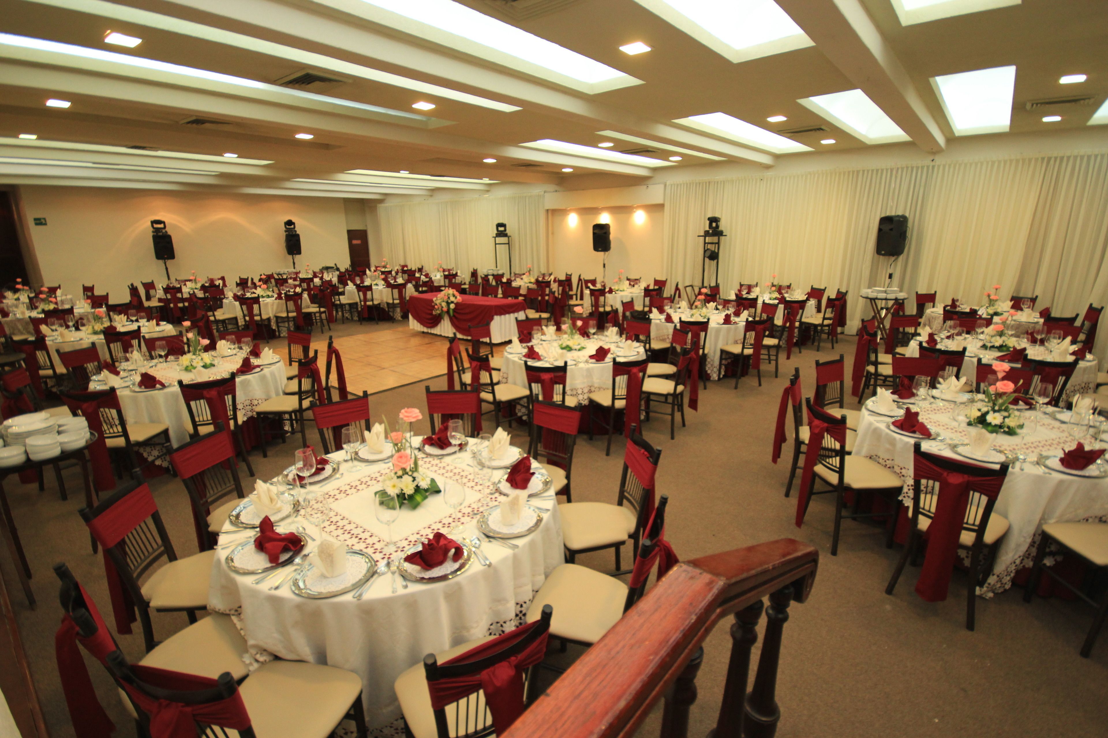 A banquet hall with round tables set for dining, equipped with chairs and tables covered in white tablecloths.