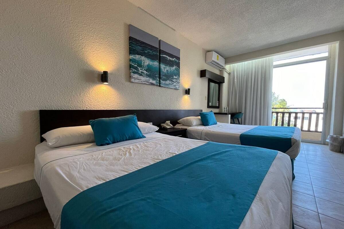 Ein Hotelzimmer mit zwei Betten, einem großen Fenster und Blick ins Freie.