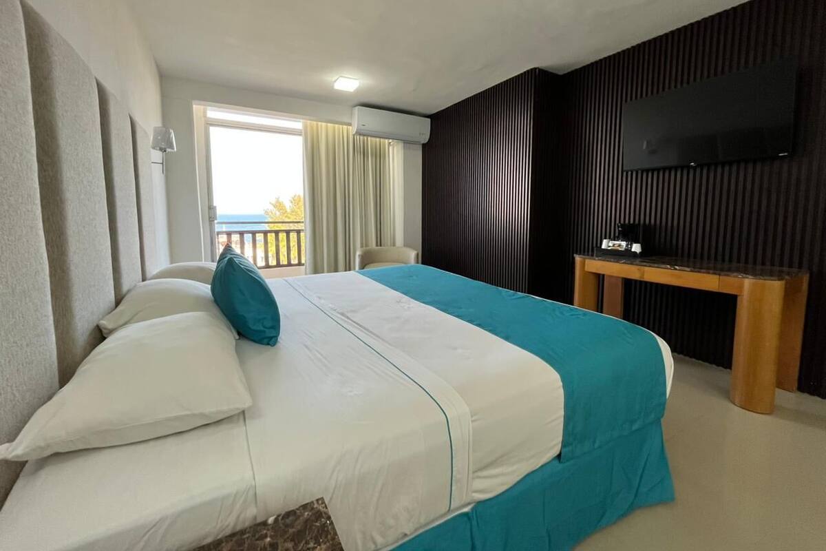 Ein Hotelzimmer mit Bett, Fernseher und Balkon.