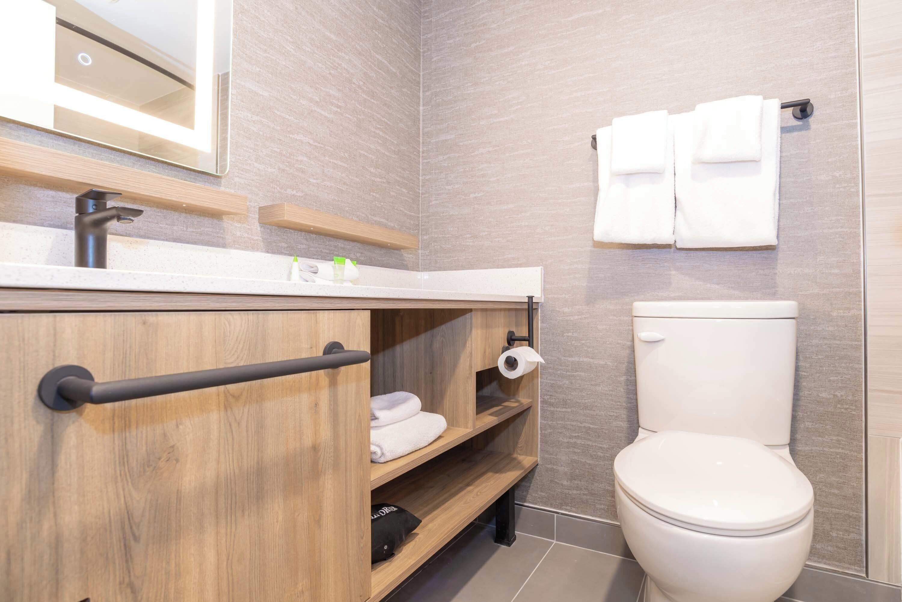 Une salle de bain moderne avec un meuble-lavabo en bois, des toilettes et un porte-serviettes.