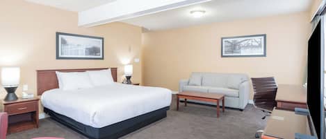 A hotel room with a bed, a sofa, a desk, and a television.
