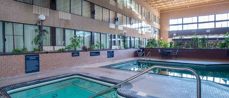An indoor swimming pool with clear water, surrounded by tiled walls and a high ceiling with metal beams.