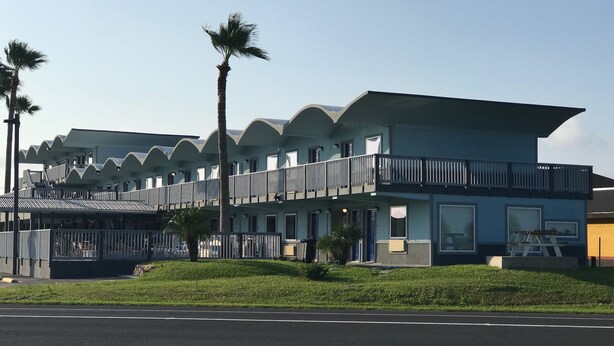 Un hotel moderno con una estructura de varios pisos, balcones y techo plano.