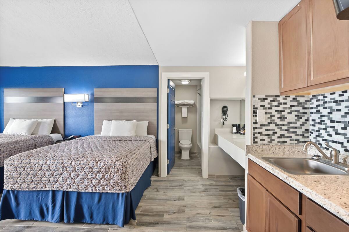 Habitación de hotel con dos camas, baño y kitchenette.
