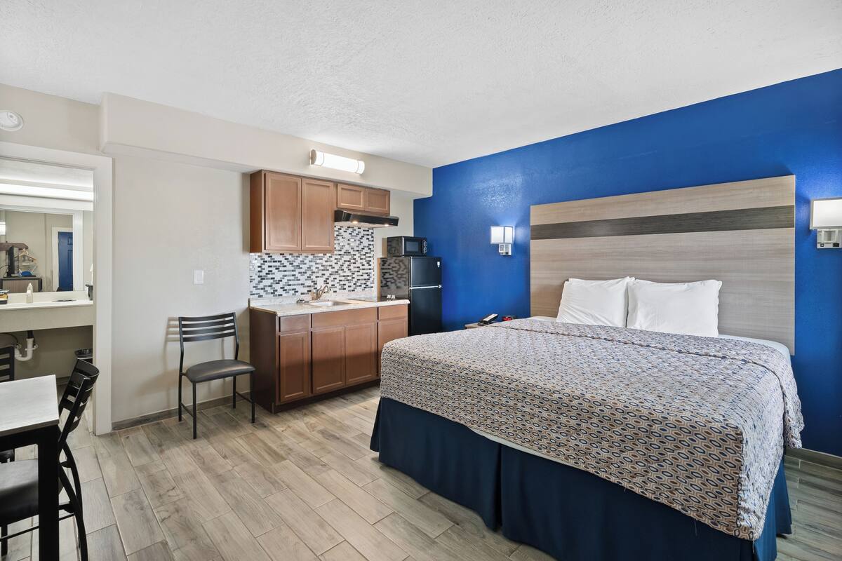 Una habitación de hotel compacta con cama, kitchenette, zona de comedor y baño.