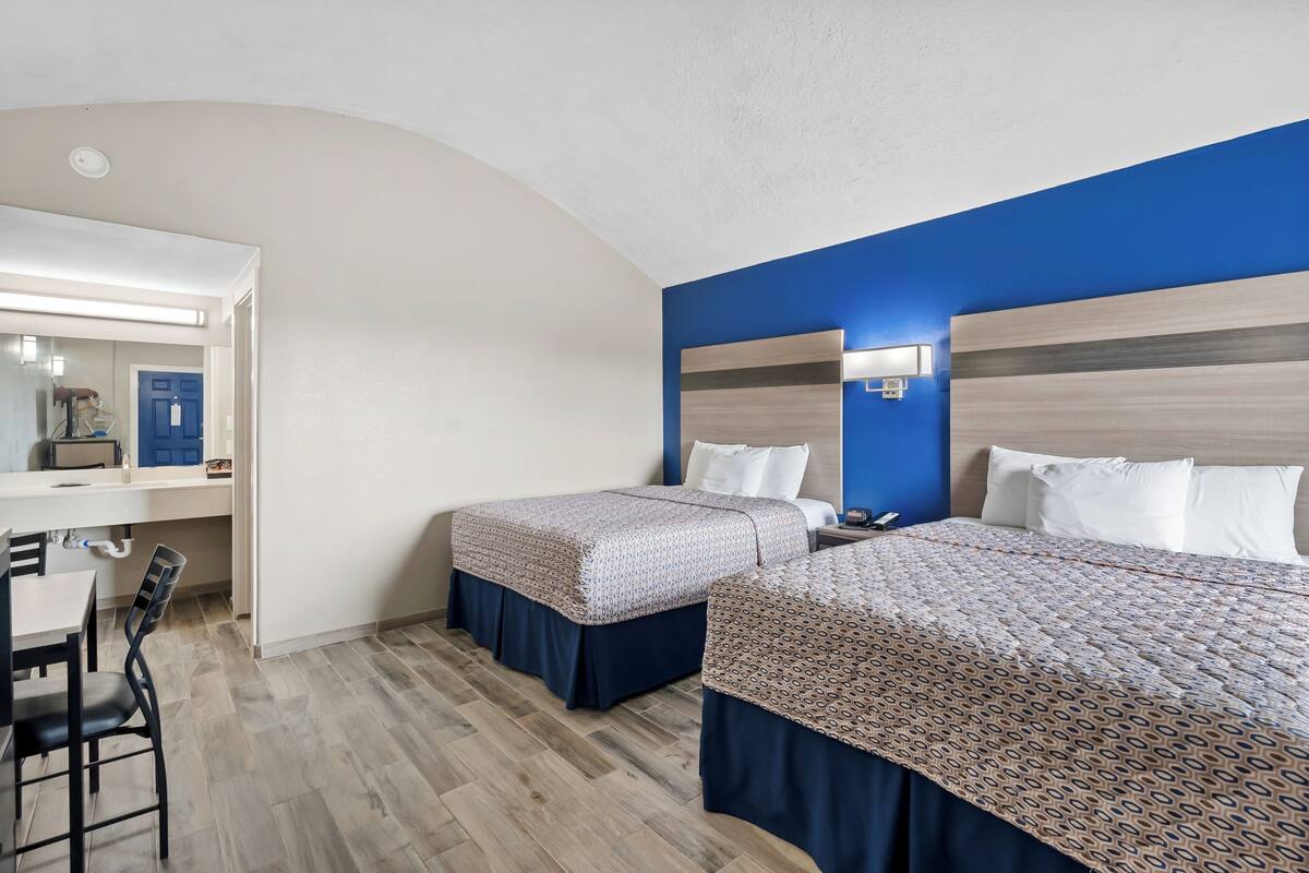 Habitación de hotel con dos camas, un escritorio y una silla.