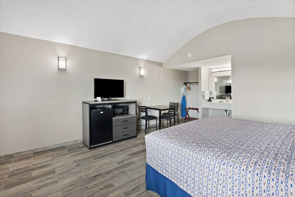 Una habitación de hotel con cama, escritorio, cómoda y televisión.