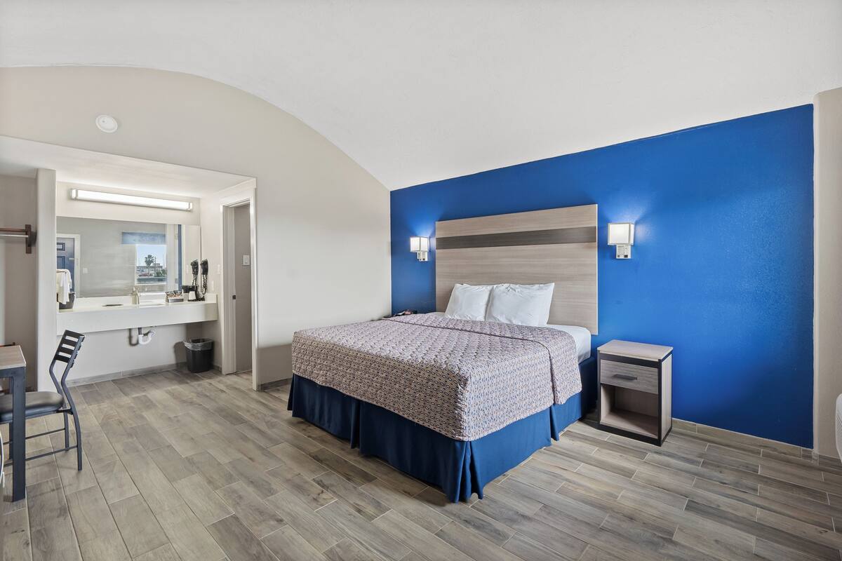 Un dormitorio con cama, mesita de noche y espejo.