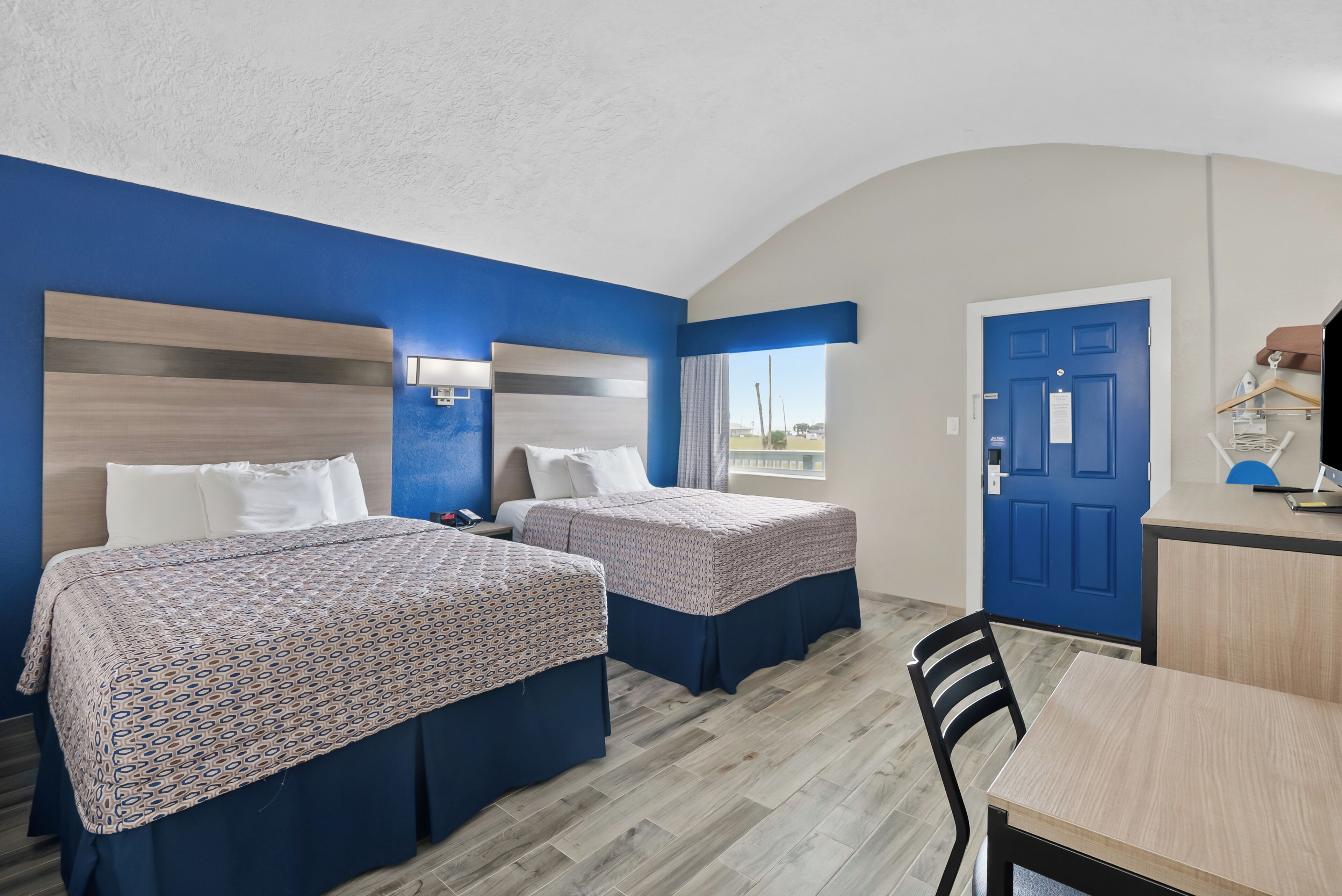 A room with two beds, a desk, and a chair.