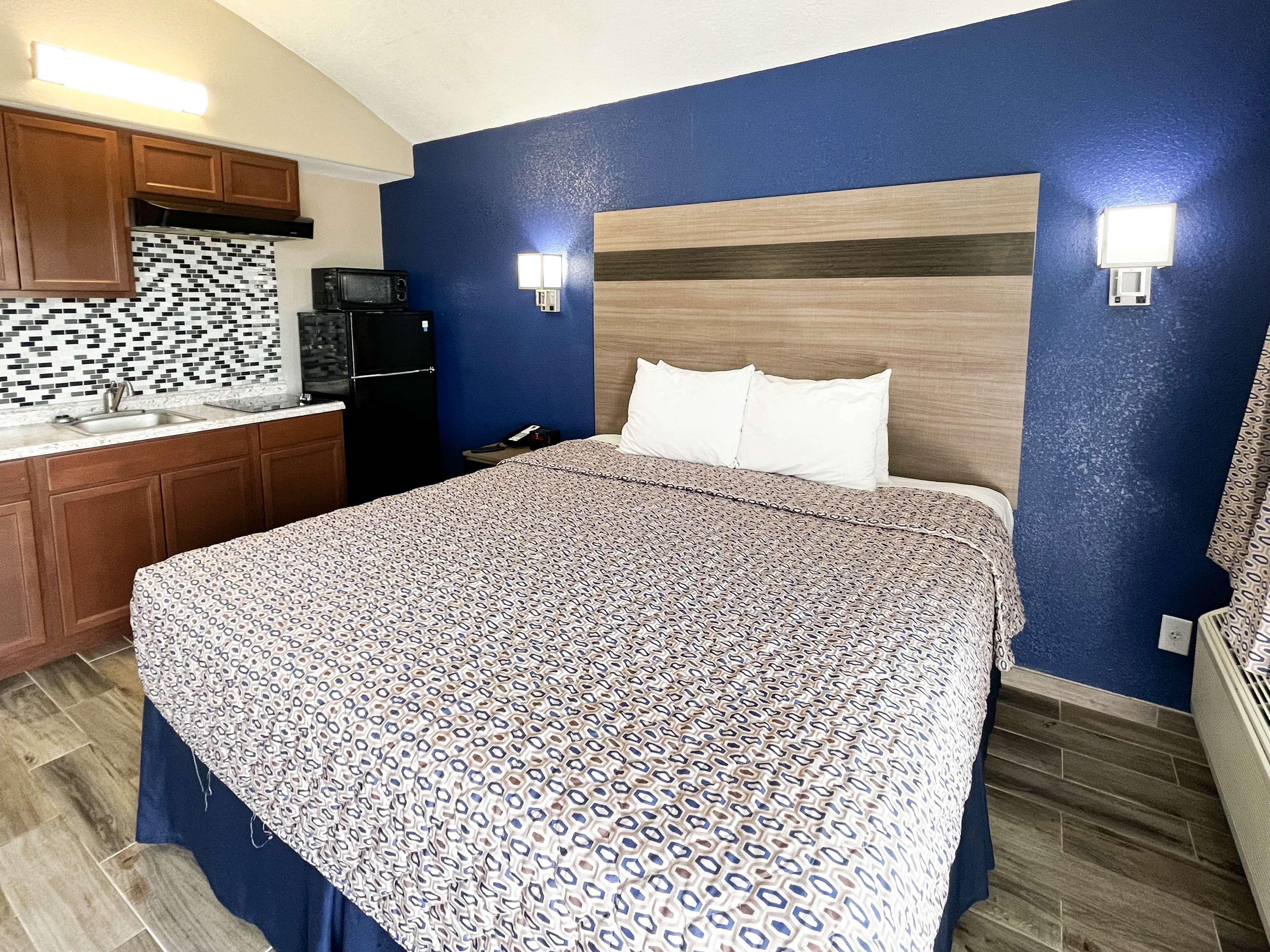 A bedroom with a bed, a microwave, and a kitchenette.