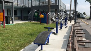 Equipos de ejercicio al aire libre, una acera y un edificio con balcón.
