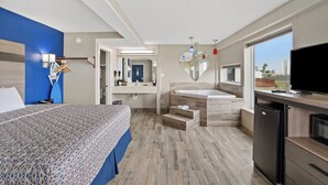 Una habitación de hotel con cama, baño con bañera, lavamanos y televisor.